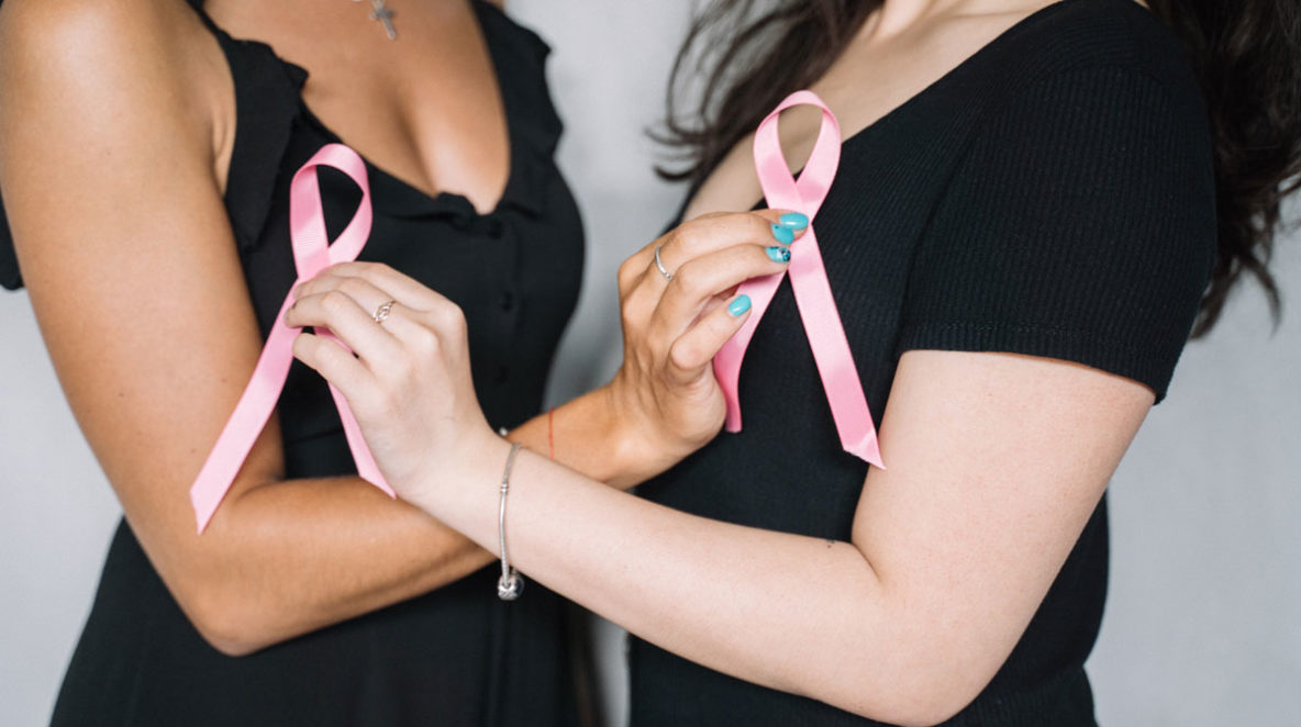 Two women holding breast cancer awareness symbols