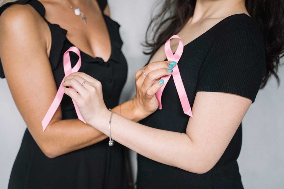 Two women holding breast cancer awareness symbols