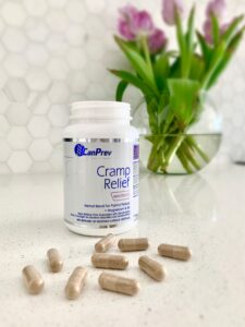 CPW Cramp relief on a table top with capsules in front of it and a vase with flowers behind it