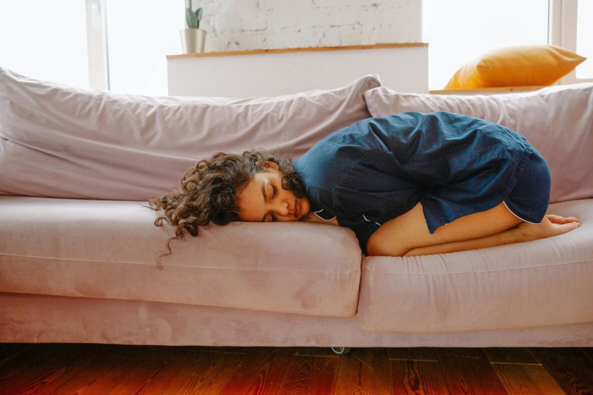 Woman curled up on couch in pain