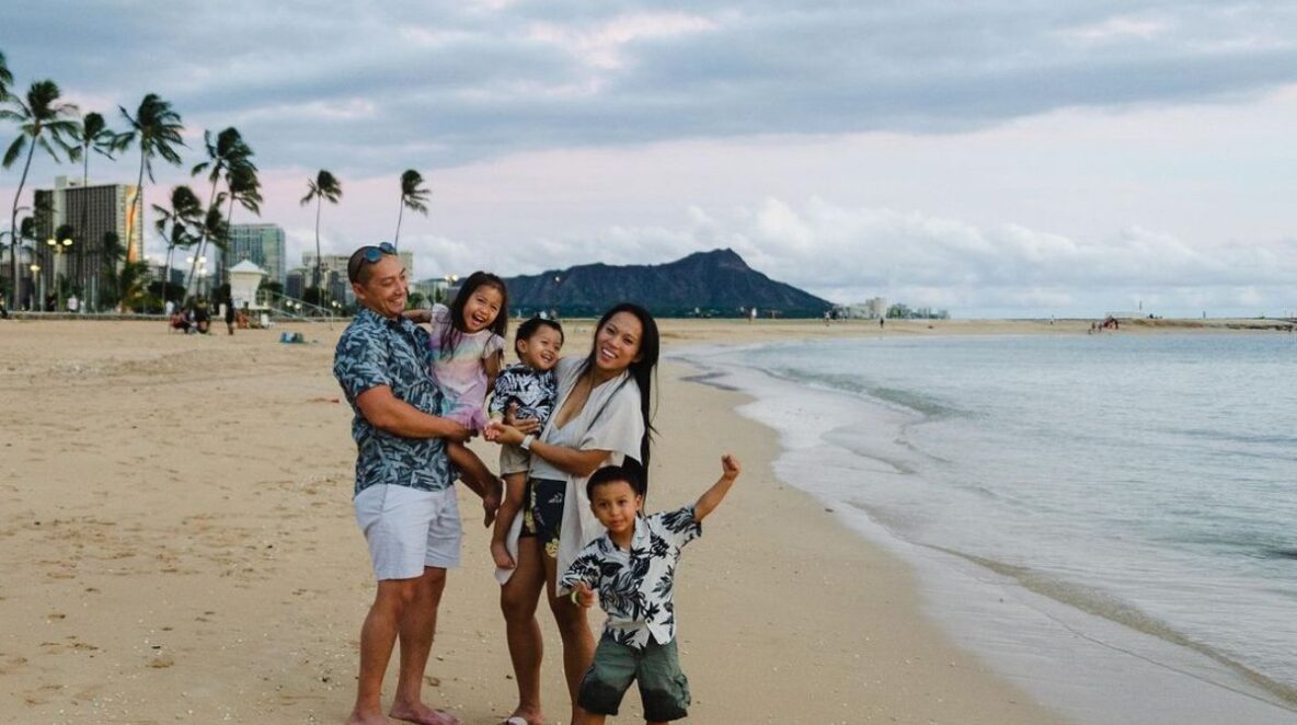 Kayla, her husband and their three kids on the beach smiling and having fun together