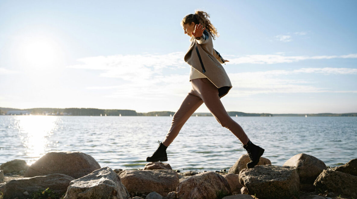 Woman balancing on rocks along a lake