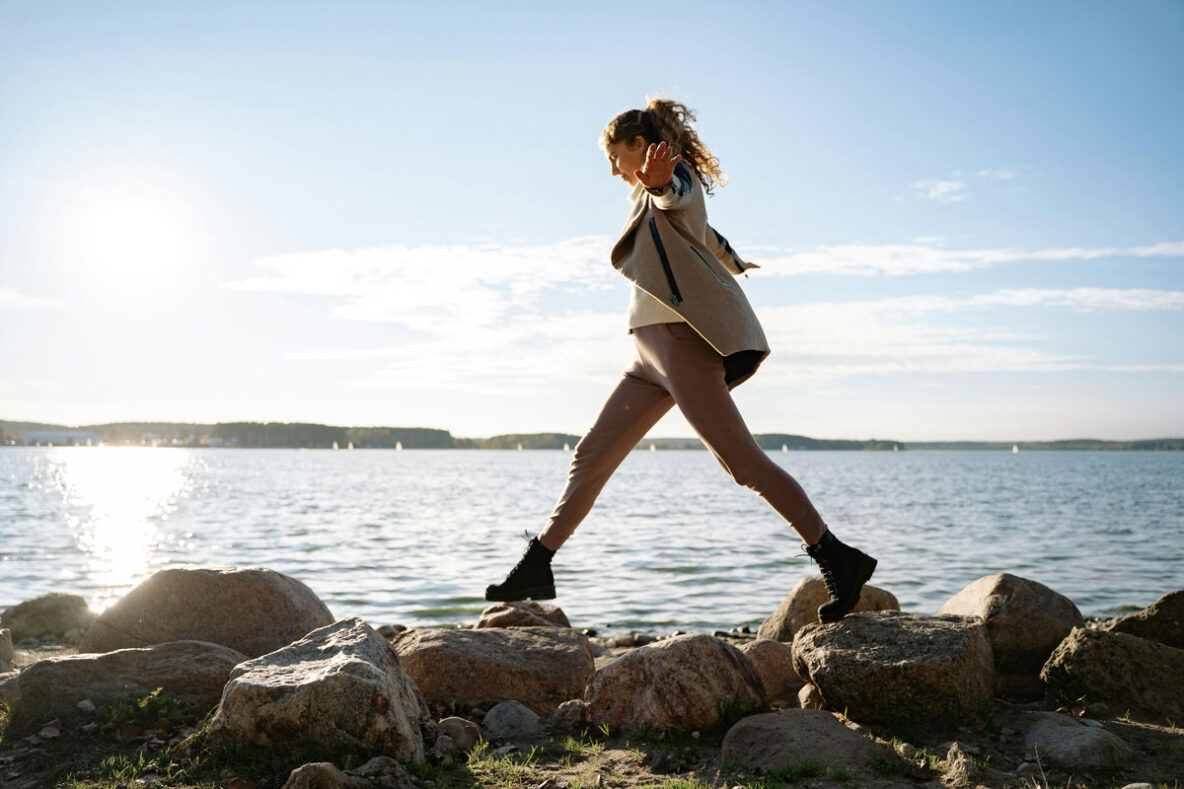 Woman balancing on rocks along a lake